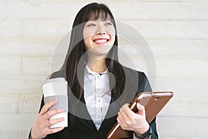 Asian business woman portrait - Young smiling Chinese girl holding smart tablet while drinking coffee ready for working