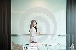 An Asian business woman presenting on blank whiteboard in meeting room