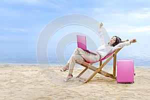 Asian business woman relax when working with laptop sitting in the beach chair on beach