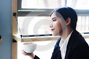 Asian business woman relaxing in coffee shop with hot coffee.