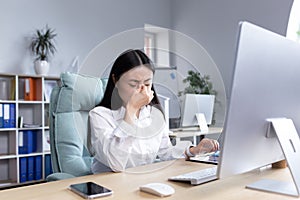 Asian business woman sick working in office, having severe headache, holding hands on head in depression and sad