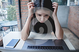 Asian business woman sitting in cafe and touching head in hands. Hand presses on the head