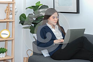 Asian business woman sitting on the sofa Relax in the living room Working using a laptop