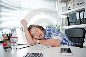 An Asian business woman is sleeping due to exhaustion from hard work on her desk