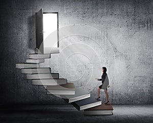 Asian business woman stepping up stair made from book