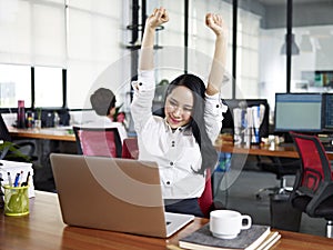 Asian business woman stretching arms in office