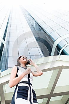 Asian business woman telephoning outside with phone