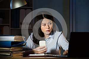 Asian business woman text message by smartphone overtime working