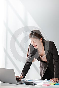 Asian Business woman using calculator and laptop for doing math finance on an office desk, tax, report, accounting