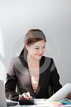 Asian Business woman using calculator and laptop for doing math finance on an office desk, tax, report, accounting