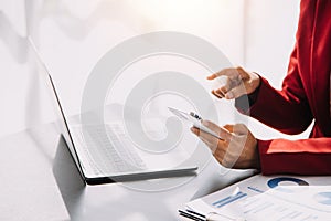 Asian Business woman using calculator and laptop for doing math finance on an office desk, tax, report, accounting, statistics,