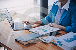 Asian Business woman using calculator and laptop for doing math finance on an office desk, tax, report, accounting, statistics,