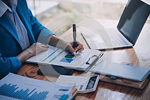 Asian Business woman using calculator and laptop for doing math finance on an office desk, tax, report, accounting, statistics,