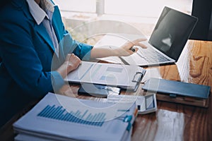 Asian Business woman using calculator and laptop for doing math finance on an office desk, tax, report, accounting, statistics,