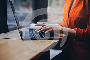 Asian Business woman using calculator and laptop for doing math finance on an office desk, tax, report, accounting, statistics,