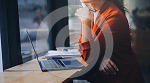 Asian Business woman using calculator and laptop for doing math finance on an office desk, tax, report, accounting, statistics,