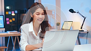 Asian business woman on video conference call, using laptop computer work late night. Remote meeting, work at home concept photo