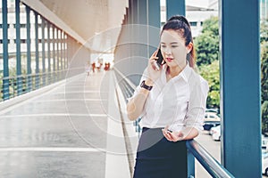 Asian business woman wearing white shirt talking smartphone for