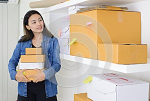 Asian business woman work at home office checking order ready to mailing or shipping with boxes and sticky note paper