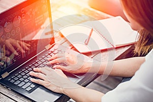 Asian Business woman work typing on laptop with graph data on screen