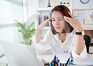 Asian business women have stress and headaches from their work at the office