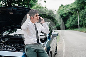 Asian businessman broken car engine breakdown his use mobile calling insurance
