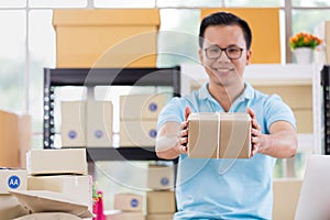 Asian businessman in casual shirt hold in parcels on hand, working in simple house office look like doing startup business.