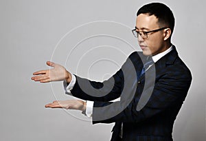 Asian businessman expert analyst manager in official suit, tie and glasses holds hands up showing something, holding