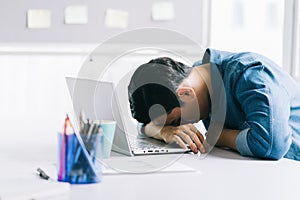 Asian businessman is falling asleep on his desk from overwork