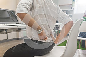 Asian businessman feels backache, sitting on the uncomfortable office chair