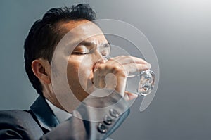 Asian Businessman in grey suit drinking water. Healthy. Copy spa
