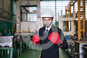 Asian businessman with hardhat and Boxing gloves ready to fight