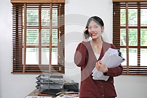 Asian businessman holding an accounting paper Financial Young Woman Spreadsheet Document Standing On The Phone Talking
