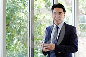 Asian Businessman holding smart phone with happy smiling face st