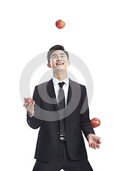 Asian businessman juggling three apples