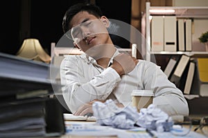 Asian businessman overtime work and feel shoulder pain in the office.