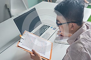 Asian businessman reading finance report and writing