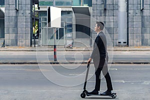 Asian businessman riding an electric scooter on the city streets to go to work in the morning. Daily commute that best reflect the