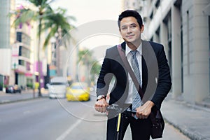 Asian businessman riding an electric scooter on the city streets to go to work in the morning. Daily commute that best reflect the photo