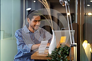 Asian businessman sitting at coffee bar in office with laptop