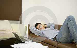 Asian businessman sleeping on sofa in living room at night