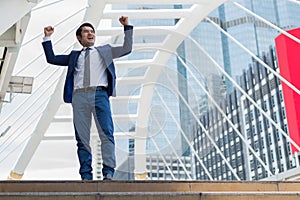 Asian businessman smile and raising up two hands to cheerful and celebrated his successful in career and mission.