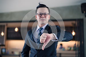 Asian businessman standing and showing thumb down.
