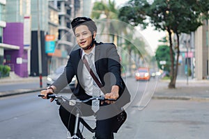 Asian businessman in a suit is riding a bicycle on the city streets for his morning commute to work. Eco Transportation Concept photo