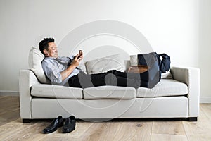 Asian businessman taking break laying on couch