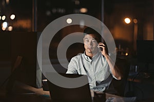 Asian businessman talking on a cellphone in a dark office