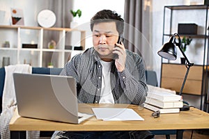 Asian businessman talking on mobile and working on laptop