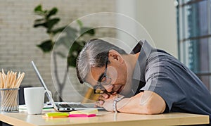 Businessman tired overworked he sleeping over a laptop computer