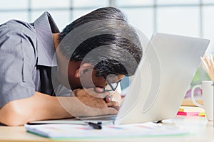 Businessman tired overworked he sleeping over a laptop computer