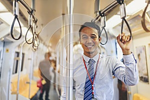 An Asian businessman is traveling a public train.